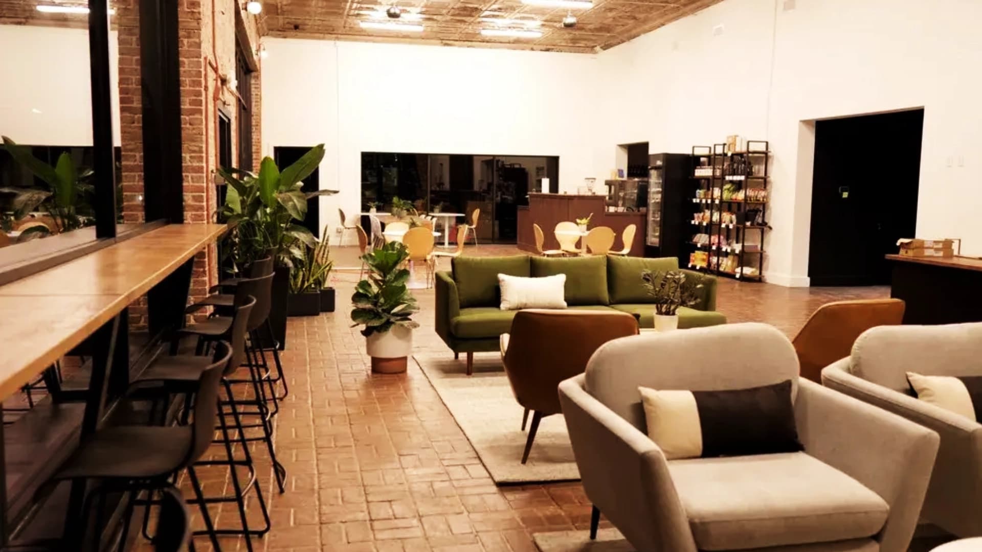 The brick-walled coworking lounge at Co-Create Innovation Hub, with shared tables, plants, and green seating